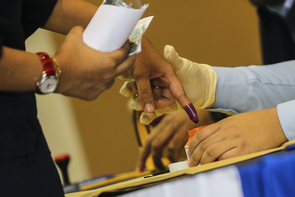 An Election Commission officer dips a voteru00e2u20acu2122s finger in indelible ink during early voting for the Seri Setia by-election at the ABABIL Multipurpose Hall in Subang September 4, 2018. u00e2u20acu201d Picture by Hari Anggara
