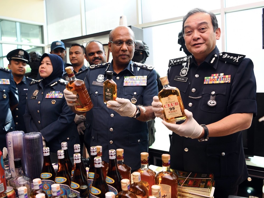 Datuk Seri Subromaniam Tholasy and Datuk Mazlan Mansor hold bottles of the seized liquor during a press conference in Klang September 28, 2018. u00e2u20acu201d Bernama pic