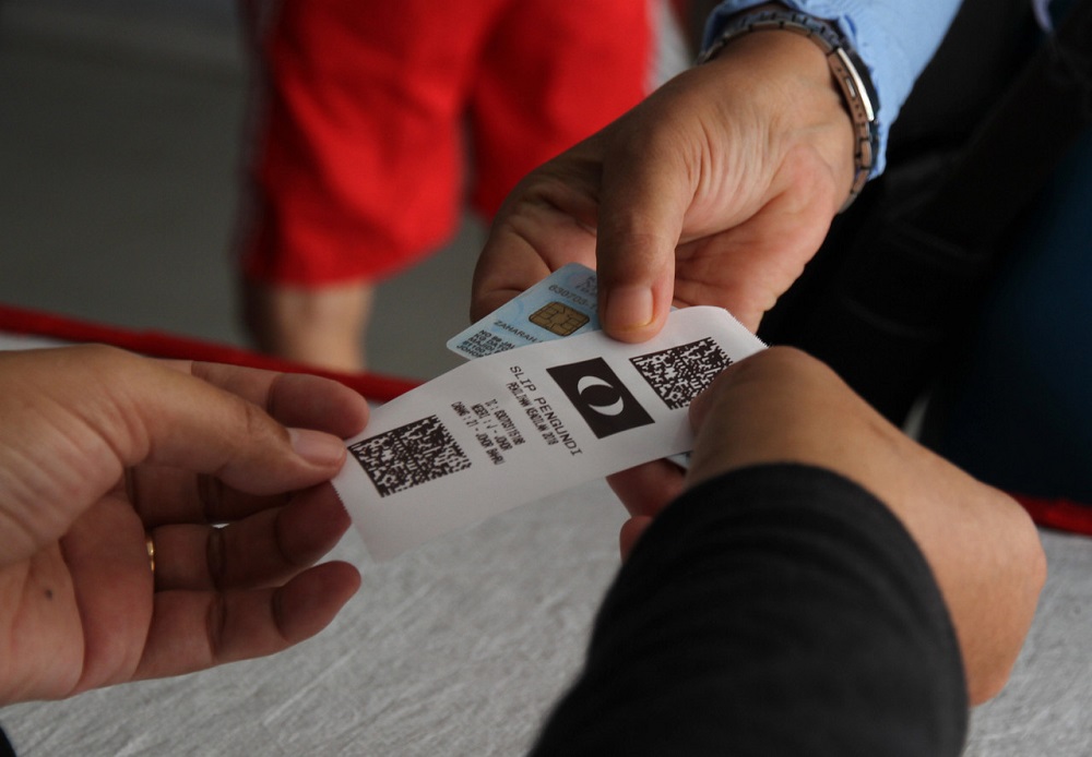 A PKR Central Electoral Committee officer hands a printed piece of paper containing a QR code to a party member during the partyu00e2u20acu2122s election in Johor Baru September 30, 2018. u00e2u20acu201d Bernama pic