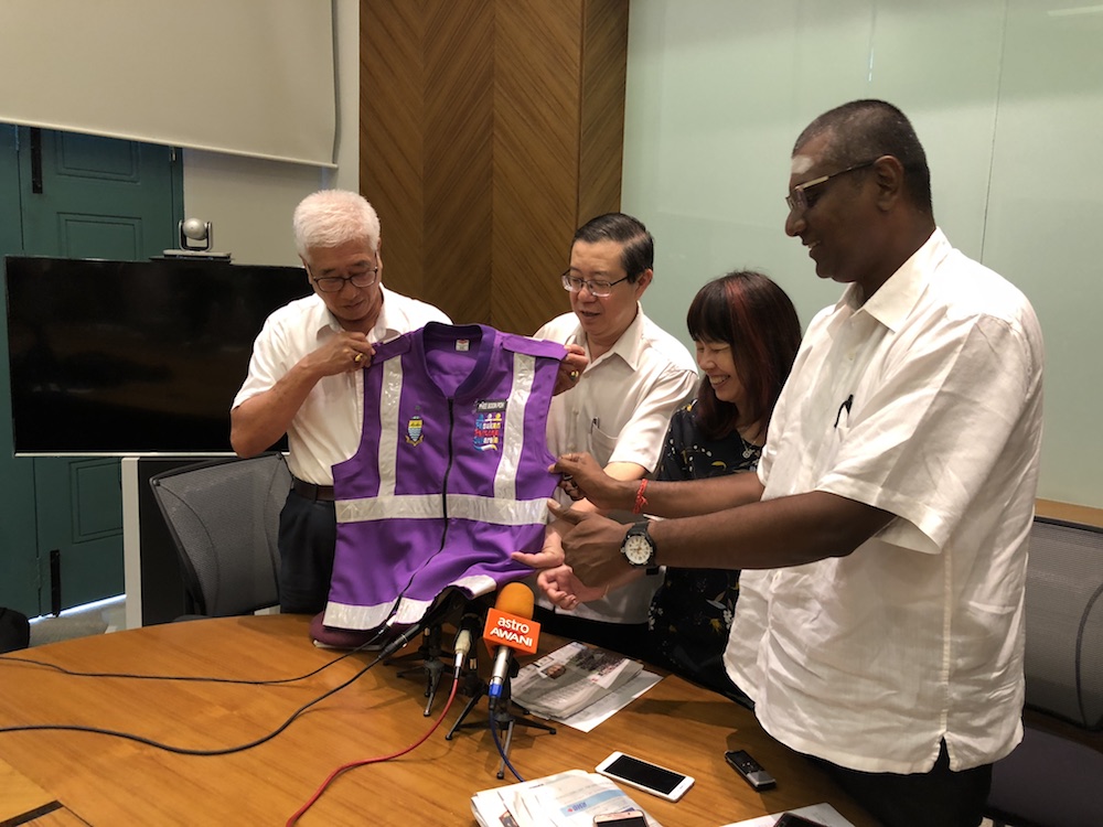 State exco Phee Boon Poh and Finance Minister Lim Guan Eng hold a purple PPS vest at a press conference in George Town September 10, 2018. u00e2u20acu201d Picture by Opalyn Mok