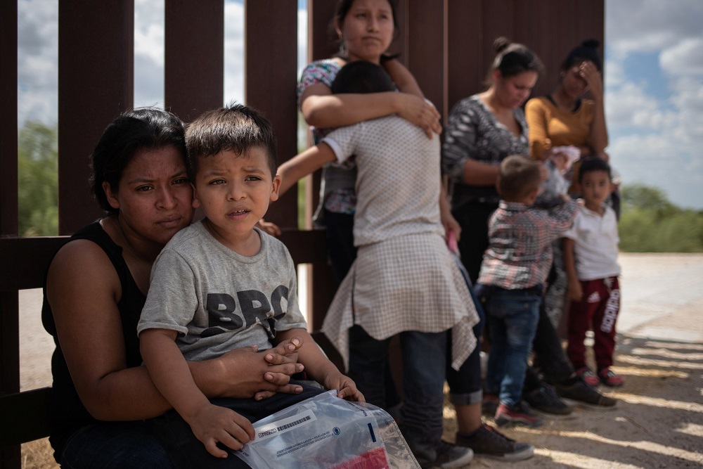 Immigrant women hold their children by the border wall as they await apprehension after illegally crossing into the US from Mexico on August 29, 2018. u00e2u20acu201d Reuters  pic
