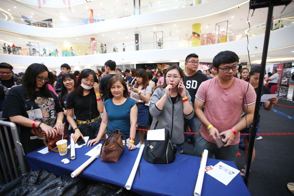 Leong Chon Wei (in pink) and Hoo Mei Yee (in gray) were the first two to get their hands on tickets. — Picture by Azinuddin Ghazali