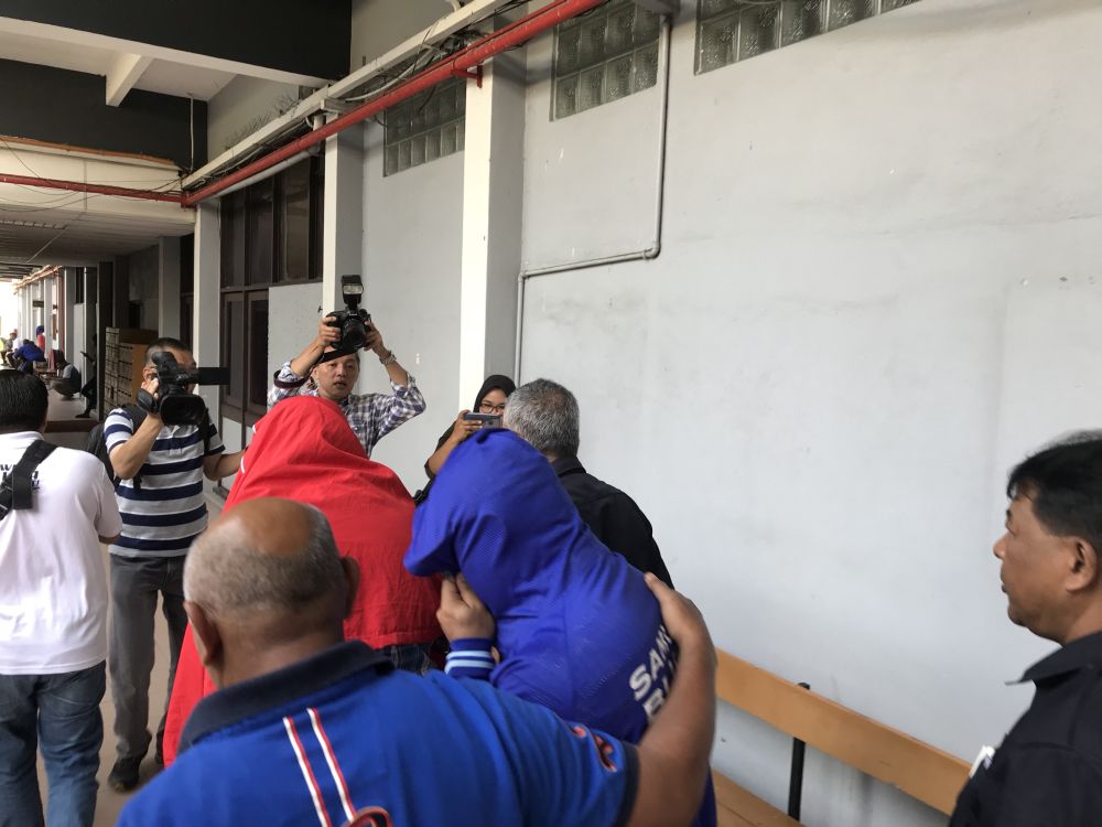 Two policemen covered their faces after being charged with corruption at the Sessions Court in Ipoh Spetember 25, 2018. u00e2u20acu2022 Picture  by John Bunyan