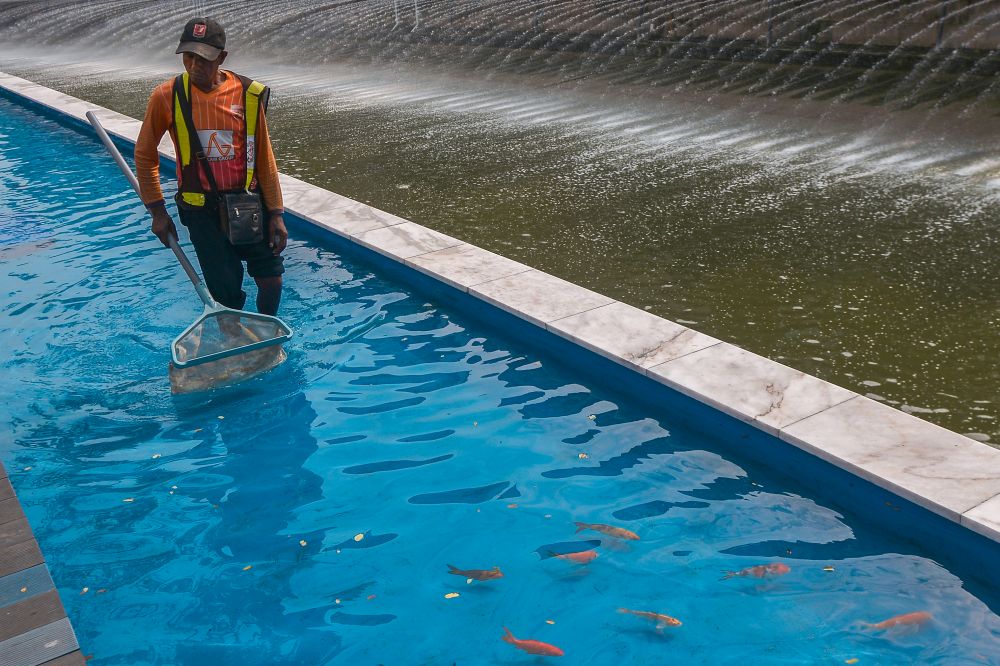 A worker cleans the fish pond alongside Sungai Gombak. The fish pond is using 100 per cent treated water collected from the drains in the city centre. — Picture by Mukhriz Hazim 