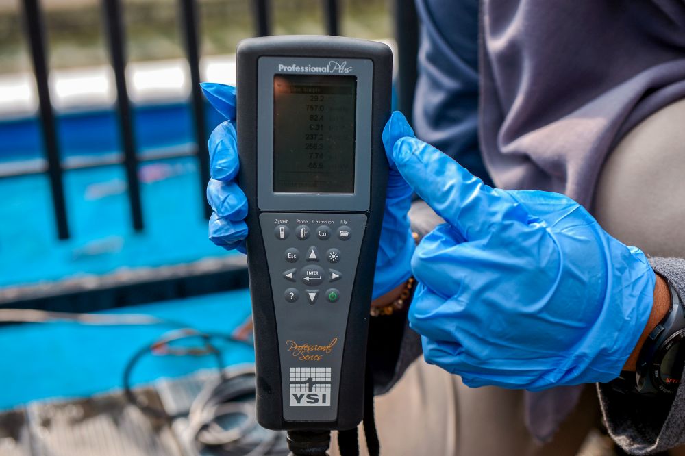A monitoring officer uses a measuring tool to check the water quality index. — Picture by Mukhriz Hazim 