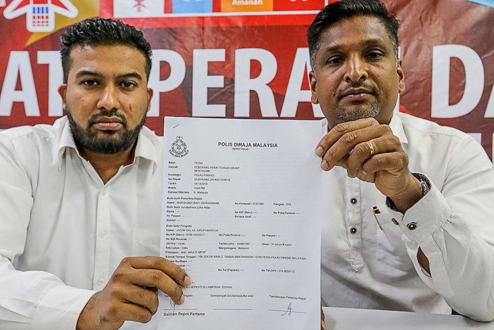 K. Jason Raj (left) and P. David Marshel shows the police report made against the immigration officer during a press conference at the Perai Service Centre. u00e2u20acu201d Picture by Sayuti Zainudin