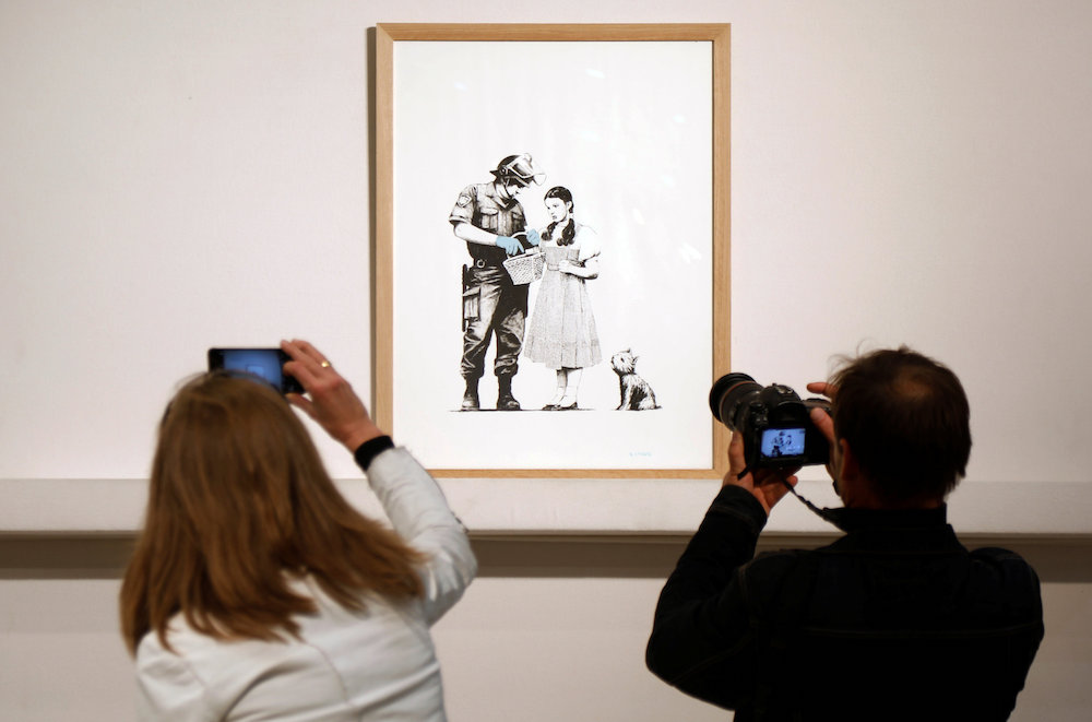 An offset lithograph entitled u00e2u20acu02dcStop and Searchu00e2u20acu2122 (2007) by British street artist Banksy is displayed before the opening of the urban art auction organised by Artcurial in Paris October 24, 2018. u00e2u20acu201d Reuters pic