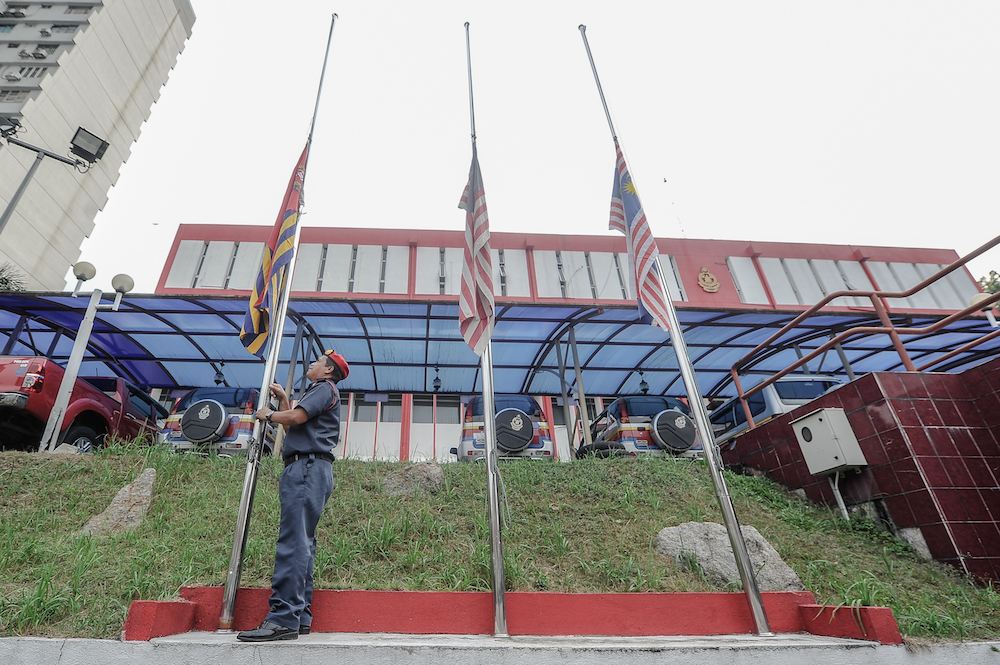 Fire department officer, Abdul Ralid Zainuddin, adjusts flags at the Fire and Rescue Departmentu00e2u20acu2122s KL headquarters to fly at half-mast in Kuala Lumpur October 5, 2018. u00e2u20acu201d Picture by Shafwan Zaidon