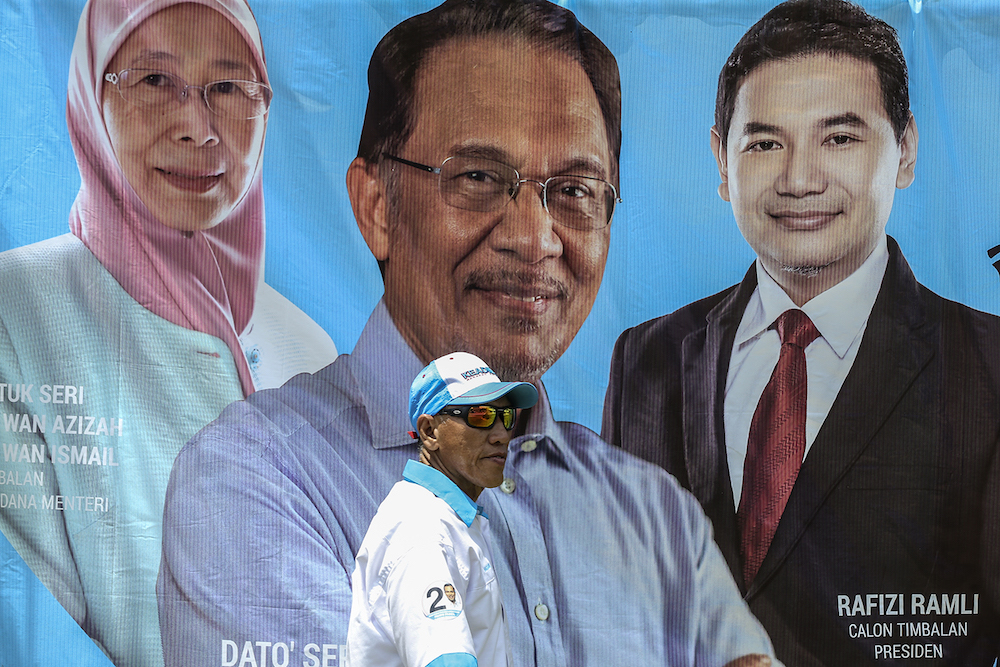 A man walks past a poster of PKR candidates during the Federal Territories PKR election in Kepong October 7, 2018. u00e2u20acu201d Picture by Azneal Ishak