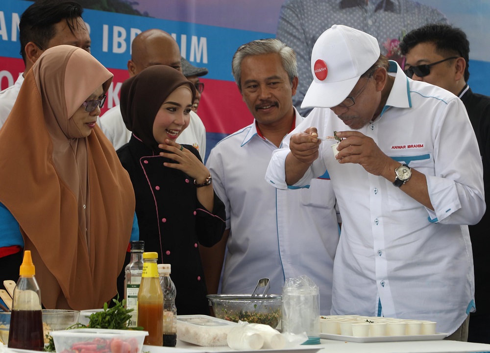 Datuk Seri Anwar Ibrahim tasting food after a food preparation demonstration. — TODAY pic