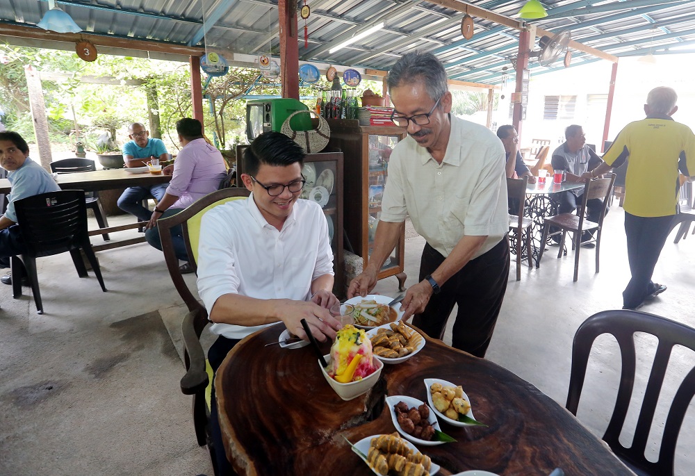 Perak state tourism, arts and culture committee chairman Tan Kar Hing (left) tucks into a bowl of 'Laksa Telaga' and other local delicacies at Kota Lama Kiri, Kuala Kangsar.