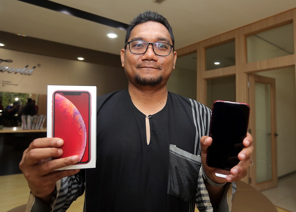 Mohd Fekry Md Nordin was the first customer to get his hands on the newly launched iPhone XR at the SNS Network outlet in Ipoh October 26, 2018. — Picture by Farhan Najib 