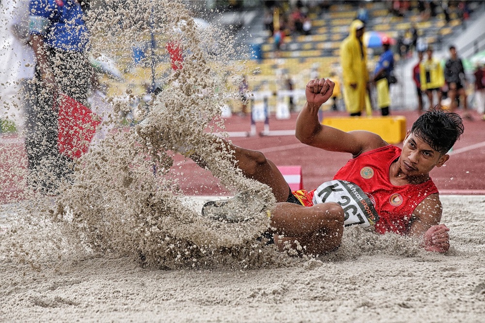 An athlete lands on the sand after his leaps during the long jump event at the 19th Malaysian Games in Perak. — Picture by Marcus Pheong