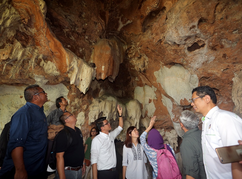 Tan (centre) points to the area of the cave wall where the fossil was found.