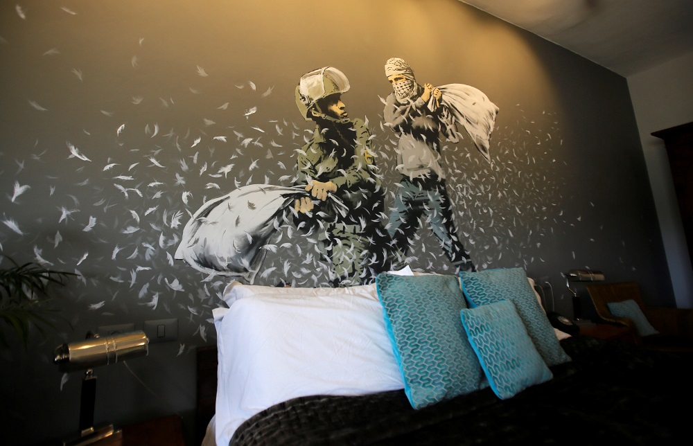 A graffiti work painted by street artist Banksy showing an Israeli soldier and masked Palestinian youth having a pillow fight, is seen in the Walled Off hotel in Bethlehem, in the occupied West Bank, October 23, 2018. u00e2u20acu201d Reuters pic