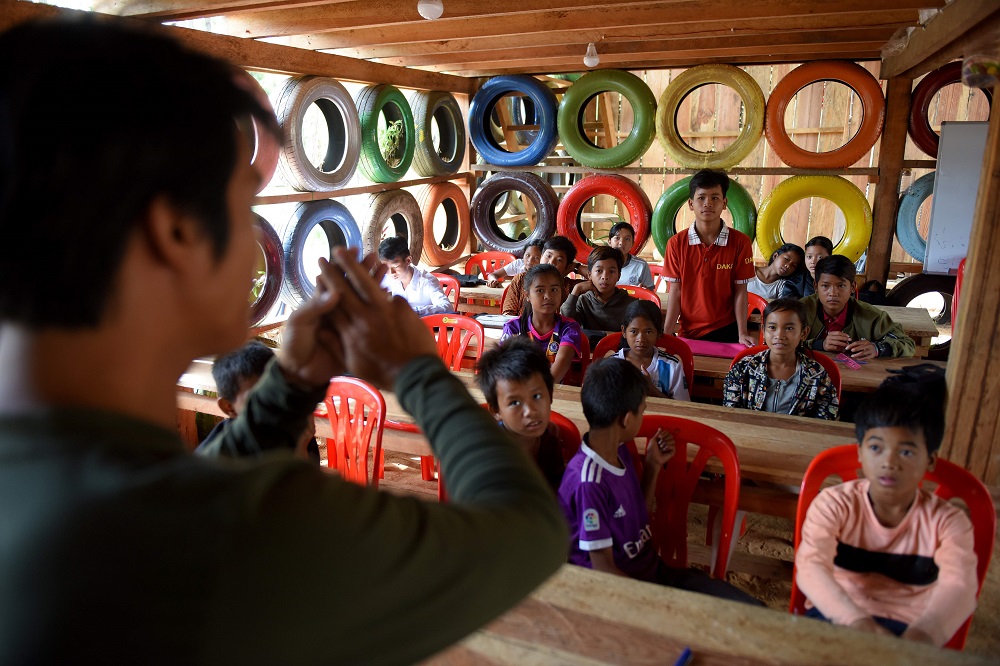 This photo taken on October 1, 2018, shows Ouk Vandey, known as the Rubbish Man, teaching students in a classroom with walls made from painted used car tyres at the Coconut School at Kirirom national park in Kampong Speu province. u00e2u20acu201d AFP pic