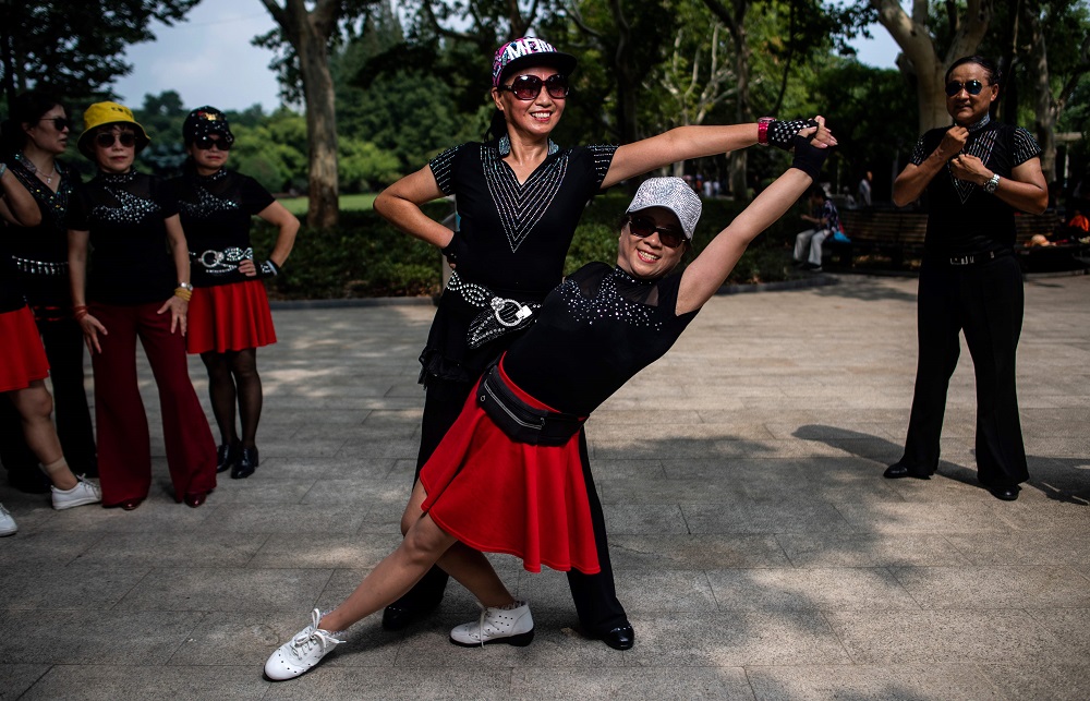 This picture taken on September 2, 2018, shows two women from a square dancing team striking a pose for a photograph in a public park in Shanghai.  u00e2u20acu201d AFP pic