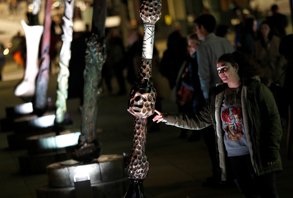 A visitor to the u00e2u20acu02dcFantastic Beasts: The Crimes of Grindelwaldu00e2u20acu2122 light installation walks among tall versions of the nine wands of the Wizarding World universe, in London October 18, 2018. u00e2u20acu201d Reuters pic