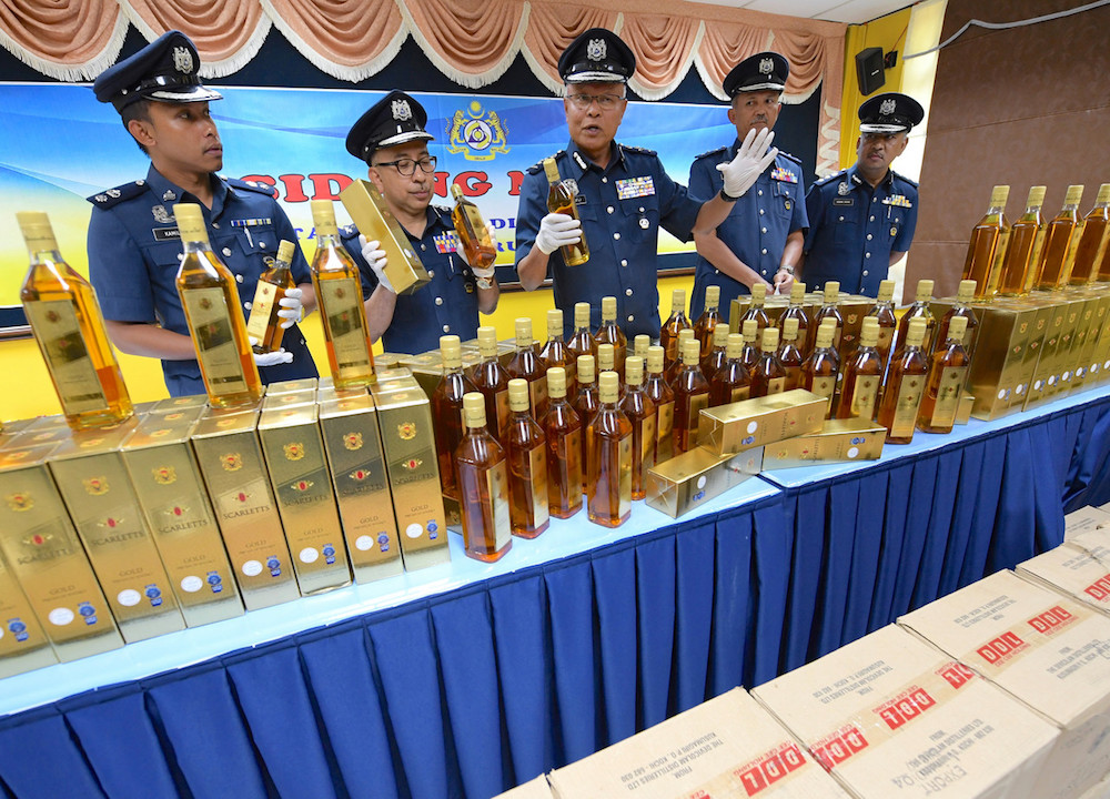 Customs deputy director (Enforcement and Compliance) Datuk Seri Zulkifli Yahya poses for pictures with the seized alcohol during a press conference in Alor Setar October 4, 2018. u00e2u20acu201d Bernama pic