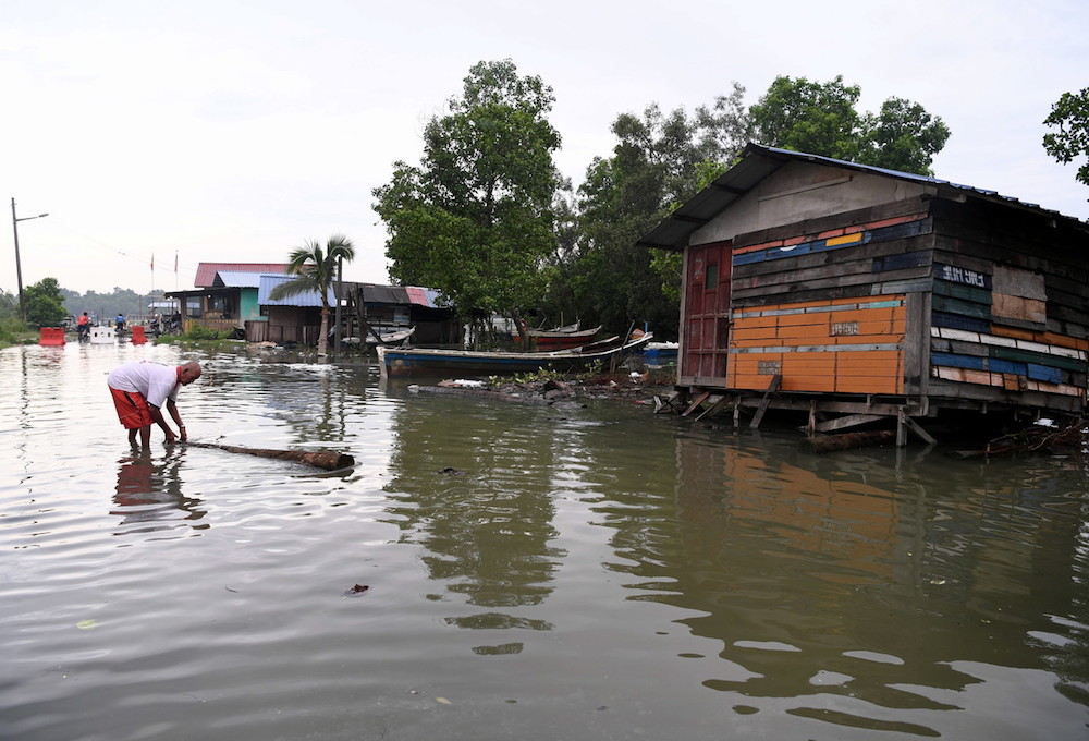 A man clears debris while standing in floodwater in Kampung Nelayan, Telok Gong in Klang October 11, 2018. u00e2u20acu201d Bernama pic 