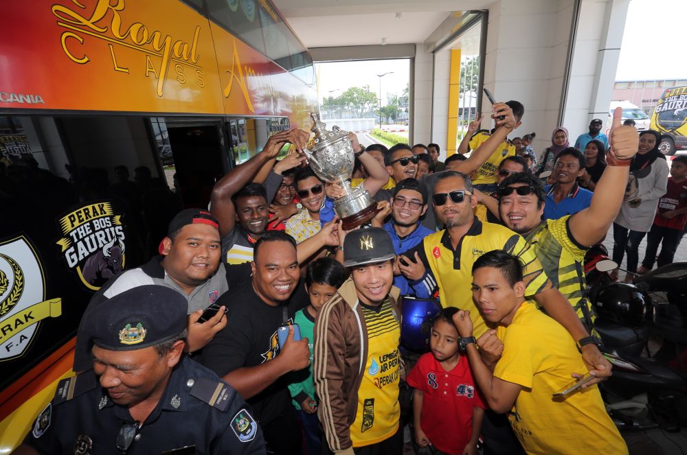 Perak FA president Hasnul Zulkarnain Abdul Munaim holds aloft the Malaysia Cup as he is mobbed by fans at the Perak Stadium, Ipoh October 28, 2018. u00e2u20acu201d Picture by Farhan Najib