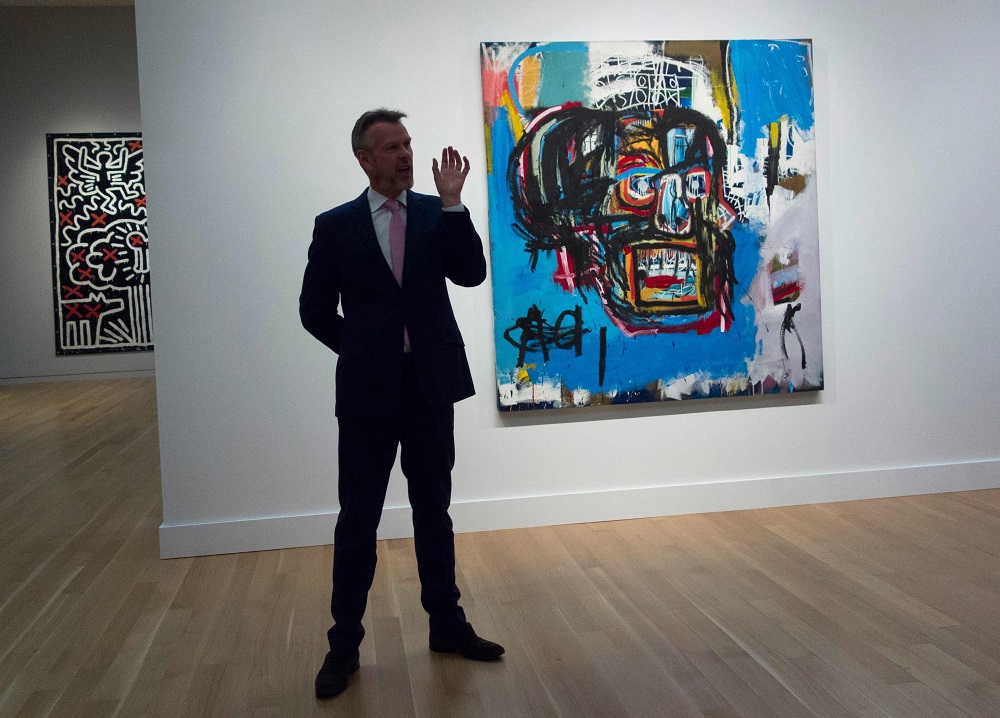 This file photo taken on May 5, 2017, shows a Sotheby’s official speaking about an untitled painting by Jean-Michel Basquiat during a media preview at Sotheby's in New York. — AFP pic