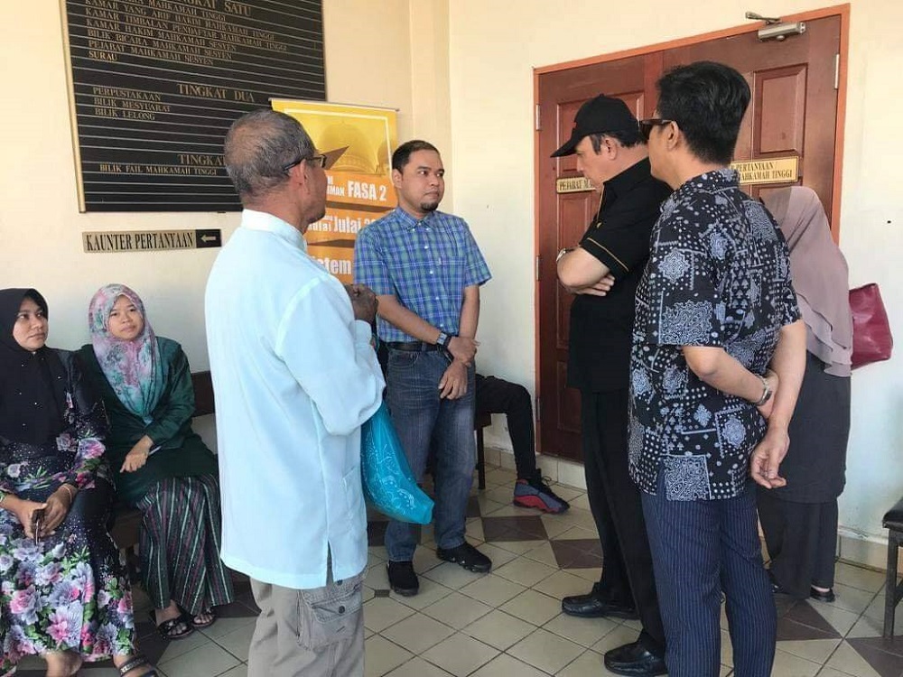 Muhammad Izwan Shah Kamal Shah (standing, second from left) speaks to Datuk Yusof Haslam (with black cap) outside the Taiping High Court. u00e2u20acu201d Picture via Facebook @sukafilma