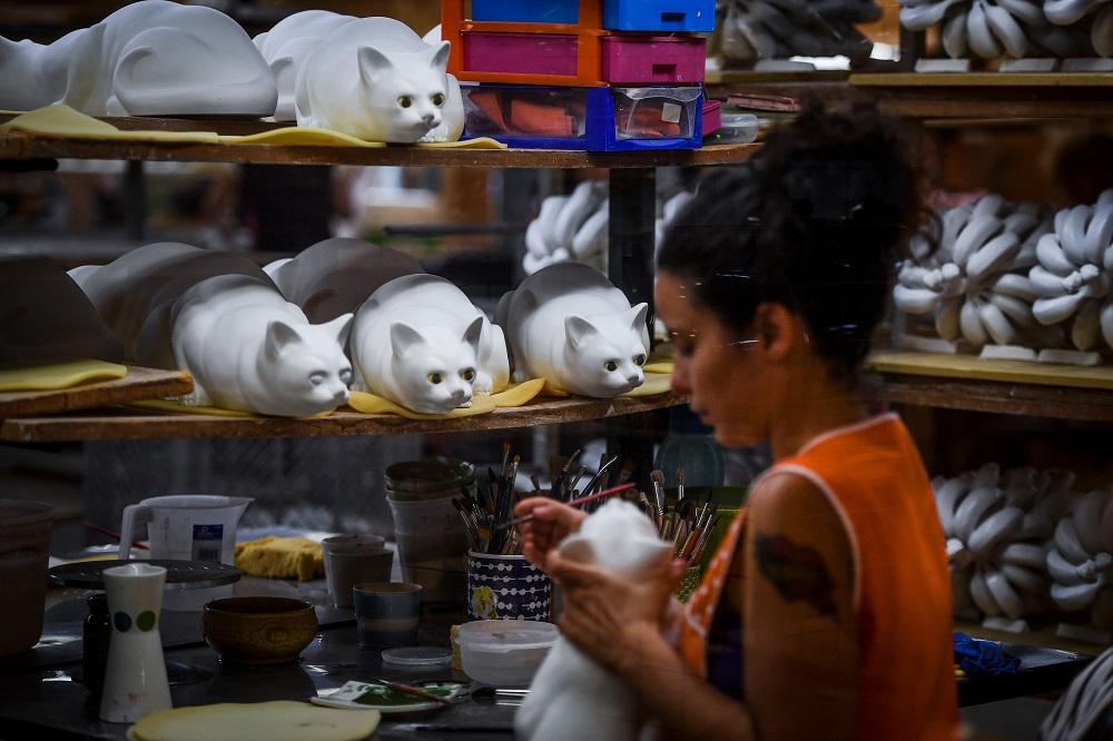 A worker paints the eyes on ceramic pieces depicting cats at Bordallo Pinheiro Factory in Caldas da Rainha on September 13, 2018. — AFP pic