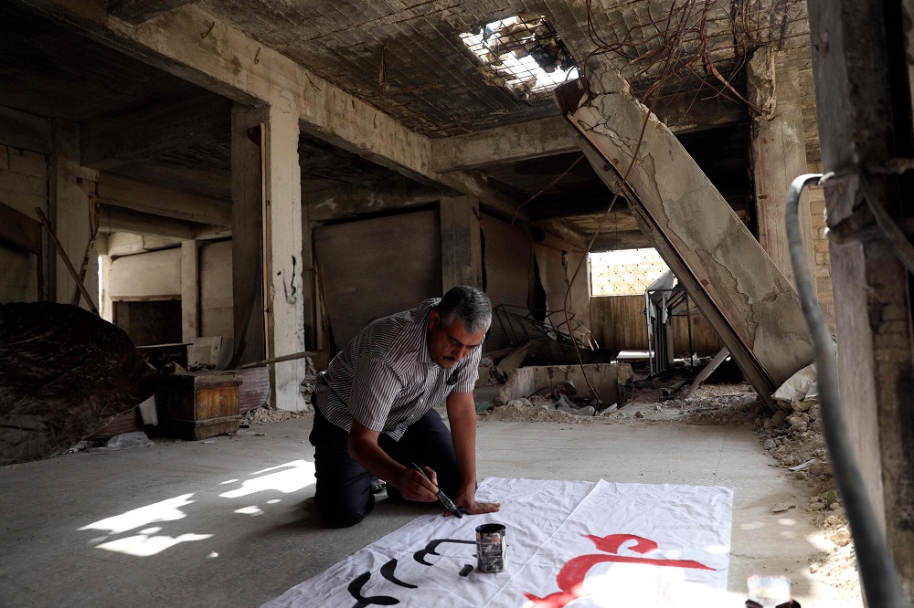 Bahr Nahhas prepares a poster ahead of a demonstration in the rebel-held town of Maaret al-Numan, in the north of Idlib province on October 19, 2018. u00e2u20acu201d AFP pic  