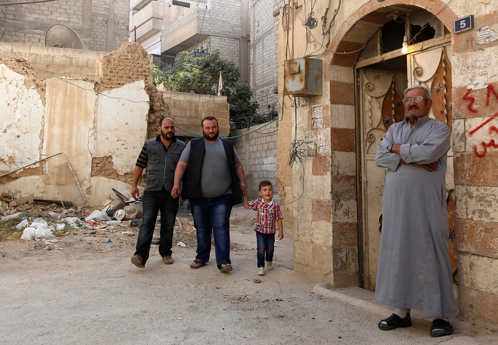 Former Syrian refugee Rawad Kurdi (second from left), 30, walks between his brother and son outside his family home in the area of Babila, south of Damascus, following his return from Lebanon October 8, 2018. u00e2u20acu201d AFP pic