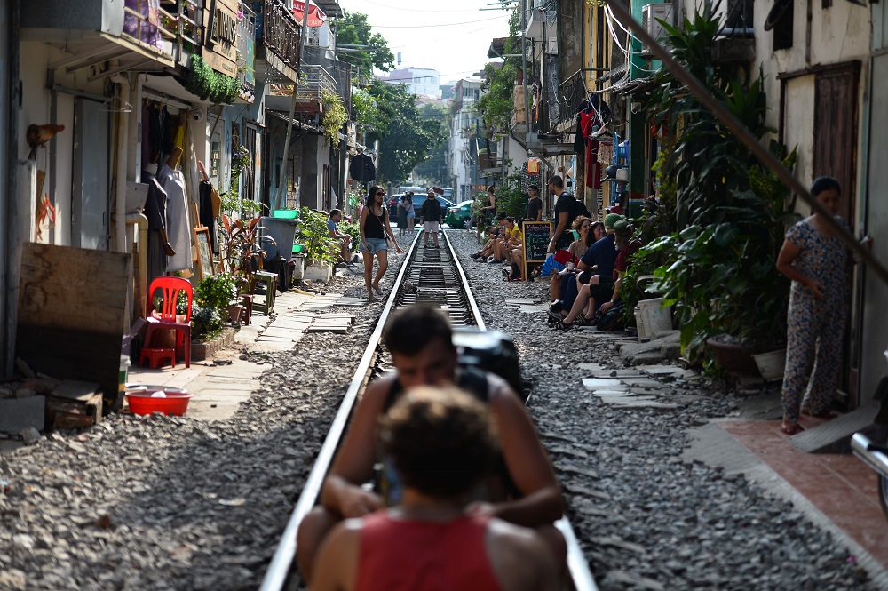 This photo taken on October 15, 2018, shows two tourists drinking on a railway track passing through an old residential district in central Hanoi. — AFP pic