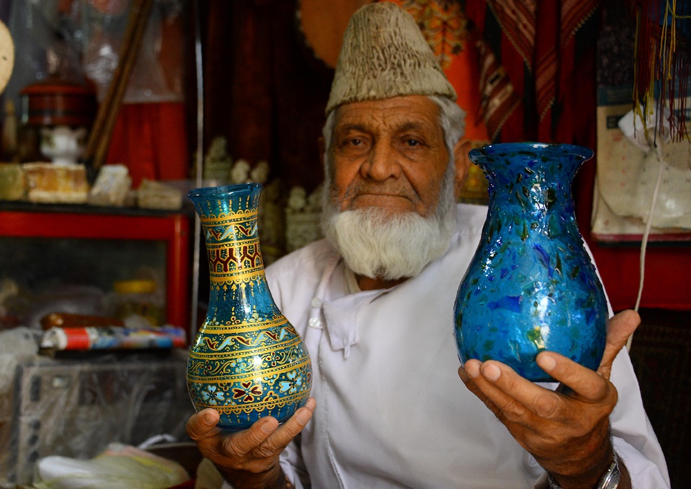 In this photo taken on August 2, 2018, Afghan man Sultan Ahmad Hamidi, 78, looks on as he sells Herati glassware, at his handicrafts shop in Herat province. u00e2u20acu201d AFP pic