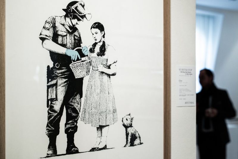 A man stands near an artwork by street artist Banksy prior to an Artcurial French auction house sale at in Paris on October 18, 2018. u00e2u20acu201d AFP pic