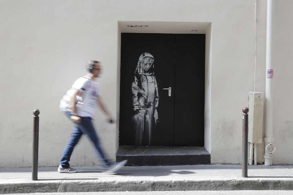 A man walks past a recent artwork by street artist Banksy in Paris. u00e2u20acu201d AFP pic