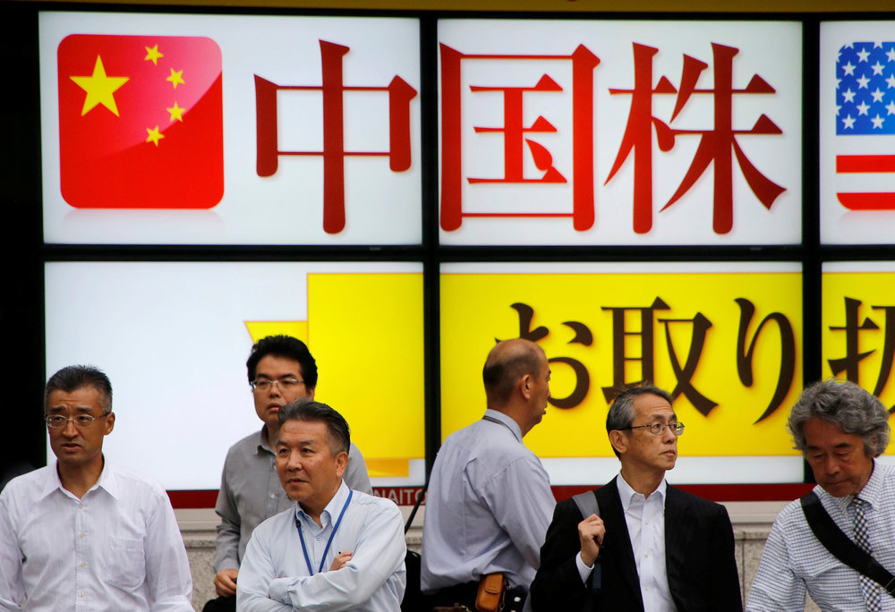 People stand in front of an electronic board showing a China stocks advertisement outside a brokerage in Tokyo September 11, 2018. u00e2u20acu201d Reuters pic
