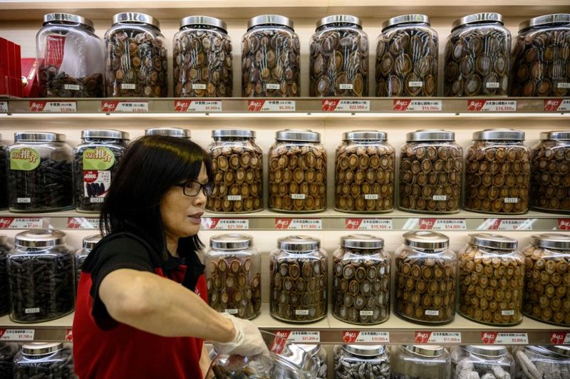 In this file photo taken on October 4, 2018, an employee holds a jar of dried products as she walks past shelves of jars containing dried abalone and other seafood goods in a shop in Hong Kong. u00e2u20acu2022 AFP pic