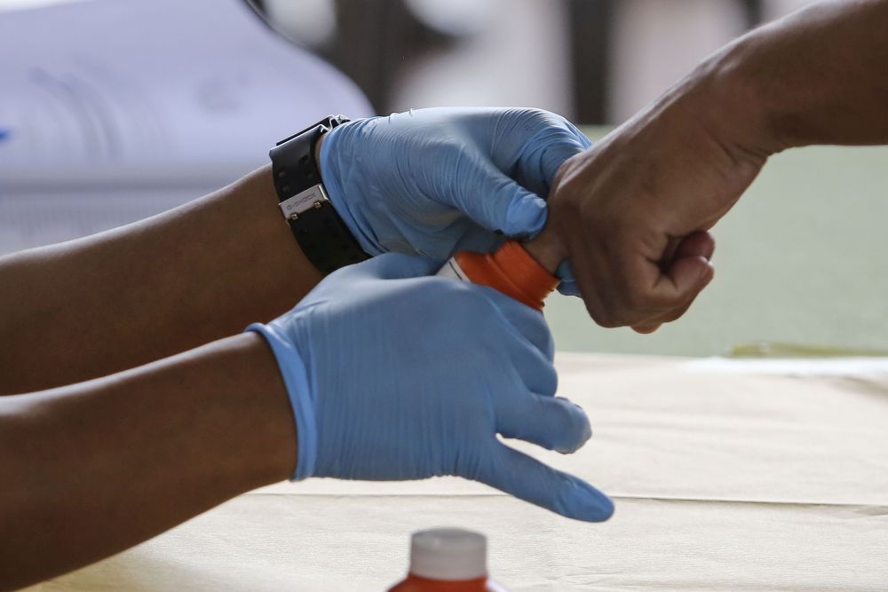 An Election Commission officer dips a military personnelu00e2u20acu2122s finger in indelible ink during early voting for the Port Dickson by-election at the Army Basic Training Centre October 9, 2018. u00e2u20acu201d Picture by Yusof Mat Isa