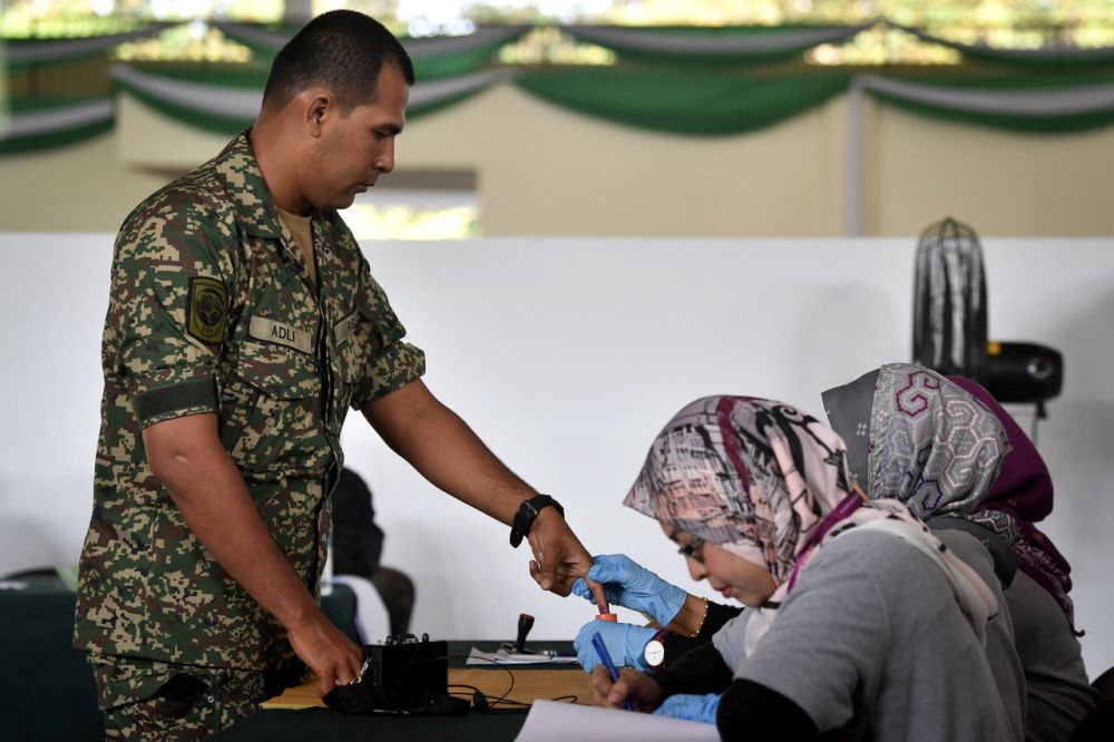 An Election Commission officer dips a military personnelu00e2u20acu2122s finger in indelible ink during early voting for the Port Dickson by-election at the Army Basic Training Centre October 9, 2018. u00e2u20acu201d Bernama pic