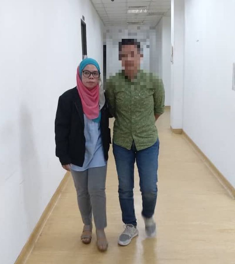 A MACC officer escorts the policewoman (right in green) who was arrested and detained to facilitate investigations for demanding and receiving bribes. — Picture courtesy of the Malaysian Anti-Corruption Commission 