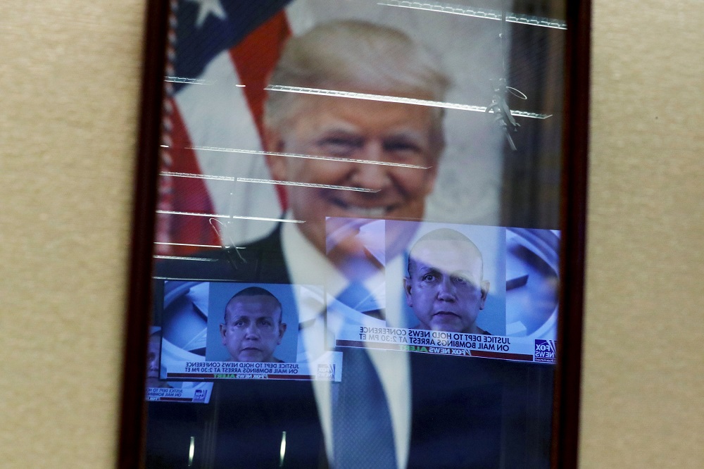 Televised pictures of parcel bombs suspect Cesar Sayoc are reflected in the official portrait of US President Donald Trump at the Justice Department in Washington October 26, 2018. u00e2u20acu201d Reuters pic