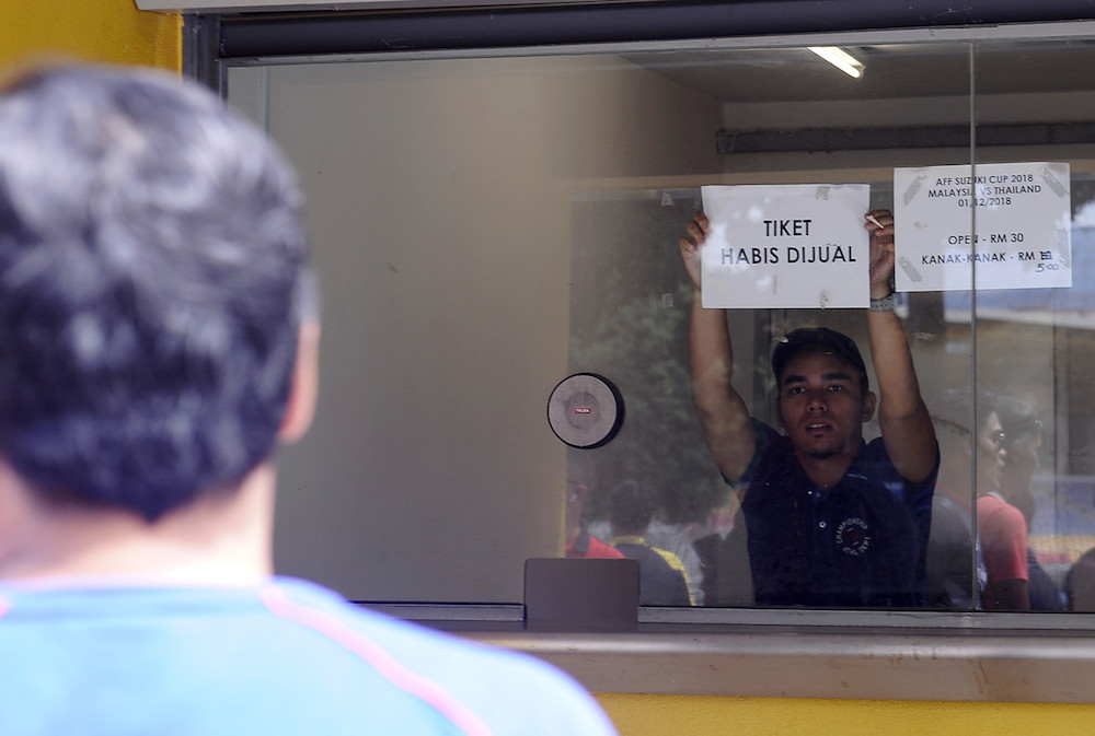 A ticket counter staff holds a sign to inform members of the public that all tickets for the semi-final clash between Malaysia and Thailand on December 1 at the Bukit Jalil National Stadium are sold out. u00e2u20acu201d Bernama pic