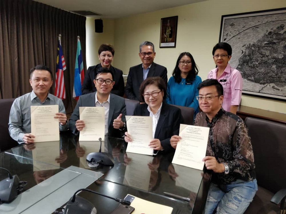 Liew, (seated, second from right) with Lau (seated, right) with the memorandum of understanding to hold Sabah's first Hong Kong film fest here next year. u00e2u20acu201d Picture by Julia Chan