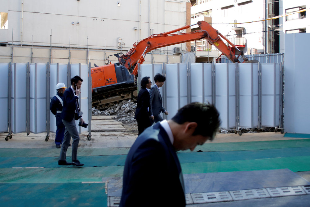 Businessmen walk past heavy machinery at a construction site in Tokyo's business district, Japan January 16, 2017. u00e2u20acu201d Reuters pic