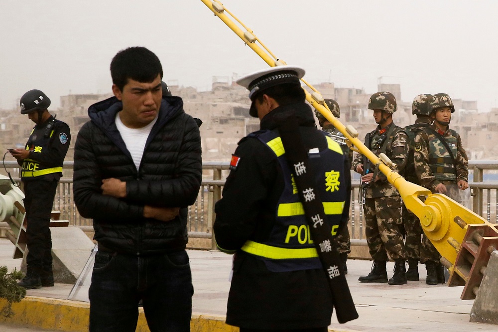 A police officer checks the identity card of a man as security forces keep watch in a street in Kashgar, Xinjiang Uighur Autonomous Region, China, March 24, 2017. u00e2u20acu201d Reuters pic