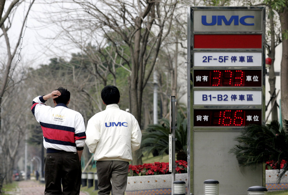 Men walk past a signboard of chipmaker United Microelectronics Corp (UMC) in Hsinchu, Taiwan January 10, 2006.  u00e2u20acu201d Reuters pic