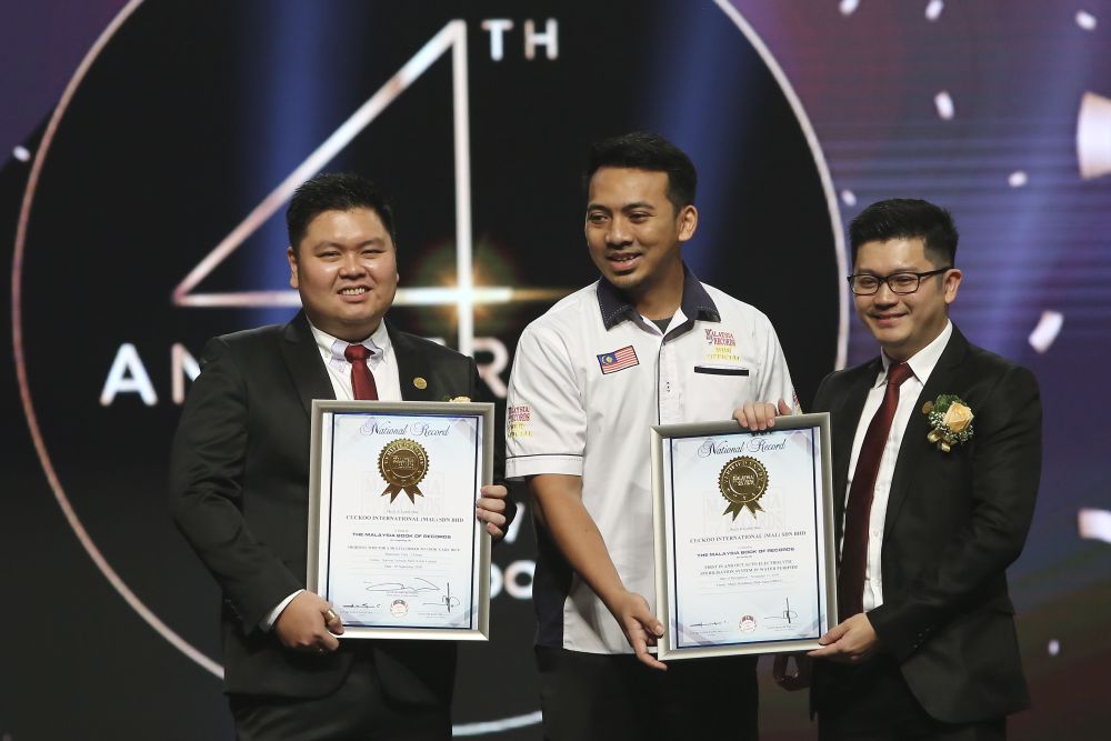 Cuckoo Indonesia chief executive officer Toh Seng Lee (left) and Cuckoo Malaysia domestic sales director Mak Wai Hoong (right) receive a Malaysia Book of Records certification from its representative Mohd Hafizi Hamdan during the ceremony.
