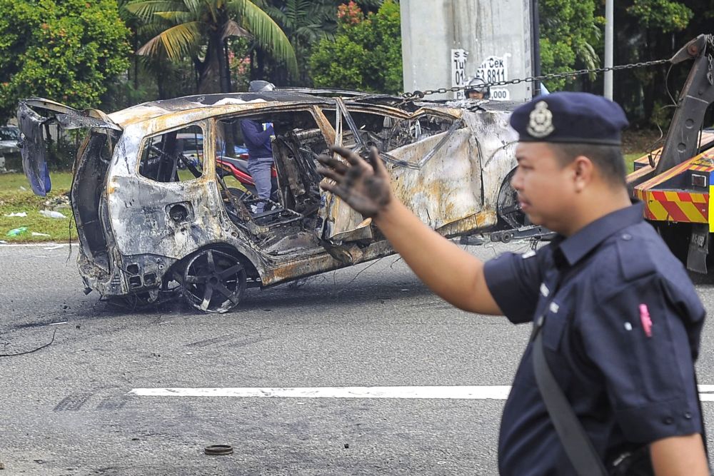 Police personnel help to clear the burnt wreckage of a car outside the Sri Maha Mariamman Devasthanam temple, November 27, 2018. u00e2u20acu2022 Picture by Shafwan Zaidon