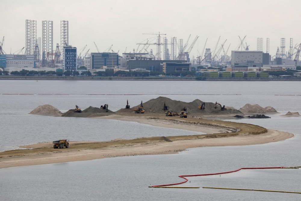 Trucks carry sand at land reclamation area overlooking Singapore's Tuas industrial area. u00e2u20acu2022 Reuters file pic