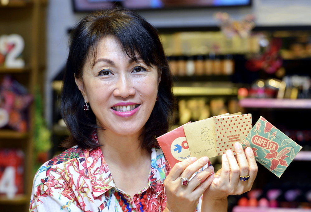 Datin Mina Cheah-Foong with the different packaging that condoms sold at The Body Shop have undergone through the years. u00e2u20acu201d Picture by Ham Abu Bakar