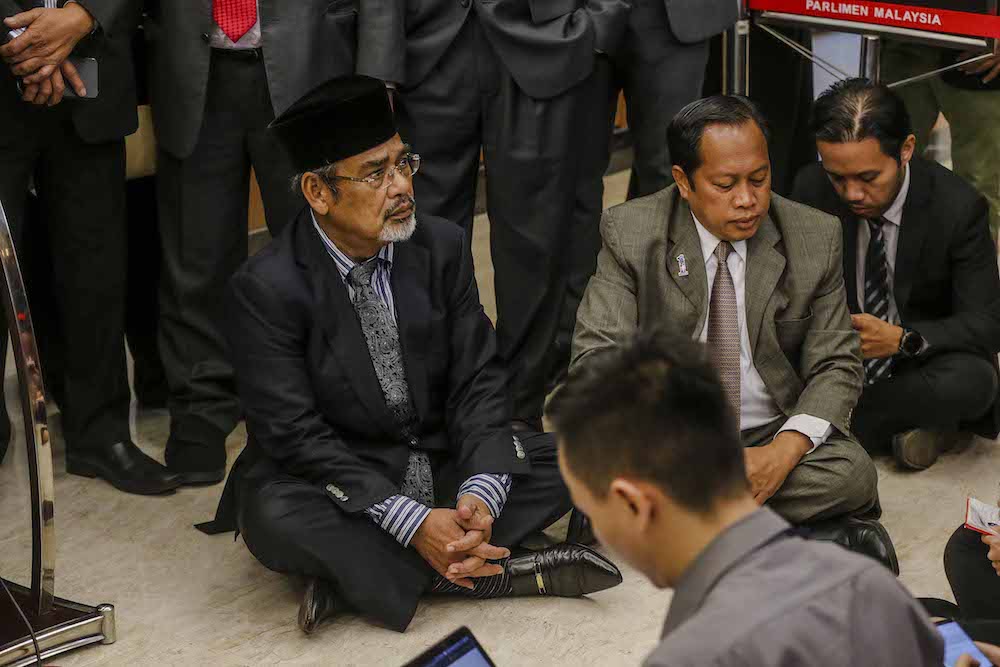 Datuk Seri Tajuddin Abdul Rahman and Datuk Seri Ahmad Maslan sit on the floor in Parliament December 10, 2018, after walking out of Dewan Rakyat in a show of protest. — Picture by Firdaus Latif